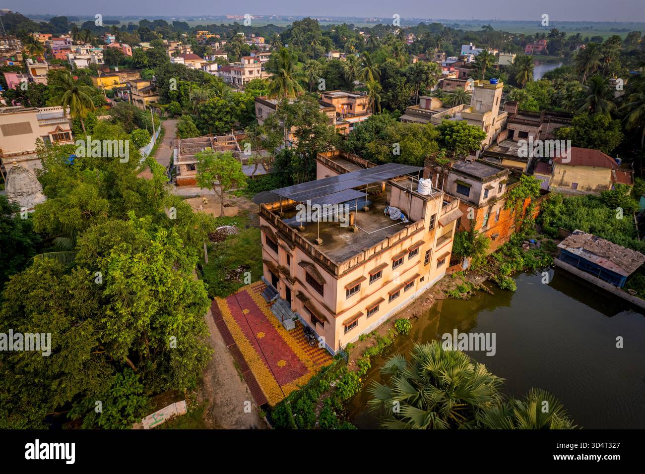 Drone aereo di tetti a pannelli solari accanto al corpo d'acqua e agli alberi nella città suburbana indiana. Foto Stock