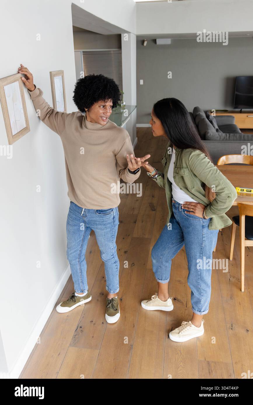 Appendere diverse coppie che regolano la cornice in legno a parete nel soggiorno, con livella a bolla d'aria Foto Stock