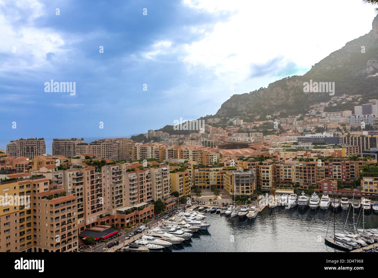 28.08.2025 FR. Monaco. Edifici a più piani circondano il porto pieni di yacht di lusso, adagiati sullo sfondo di un'alta collina rocciosa. Foto Stock
