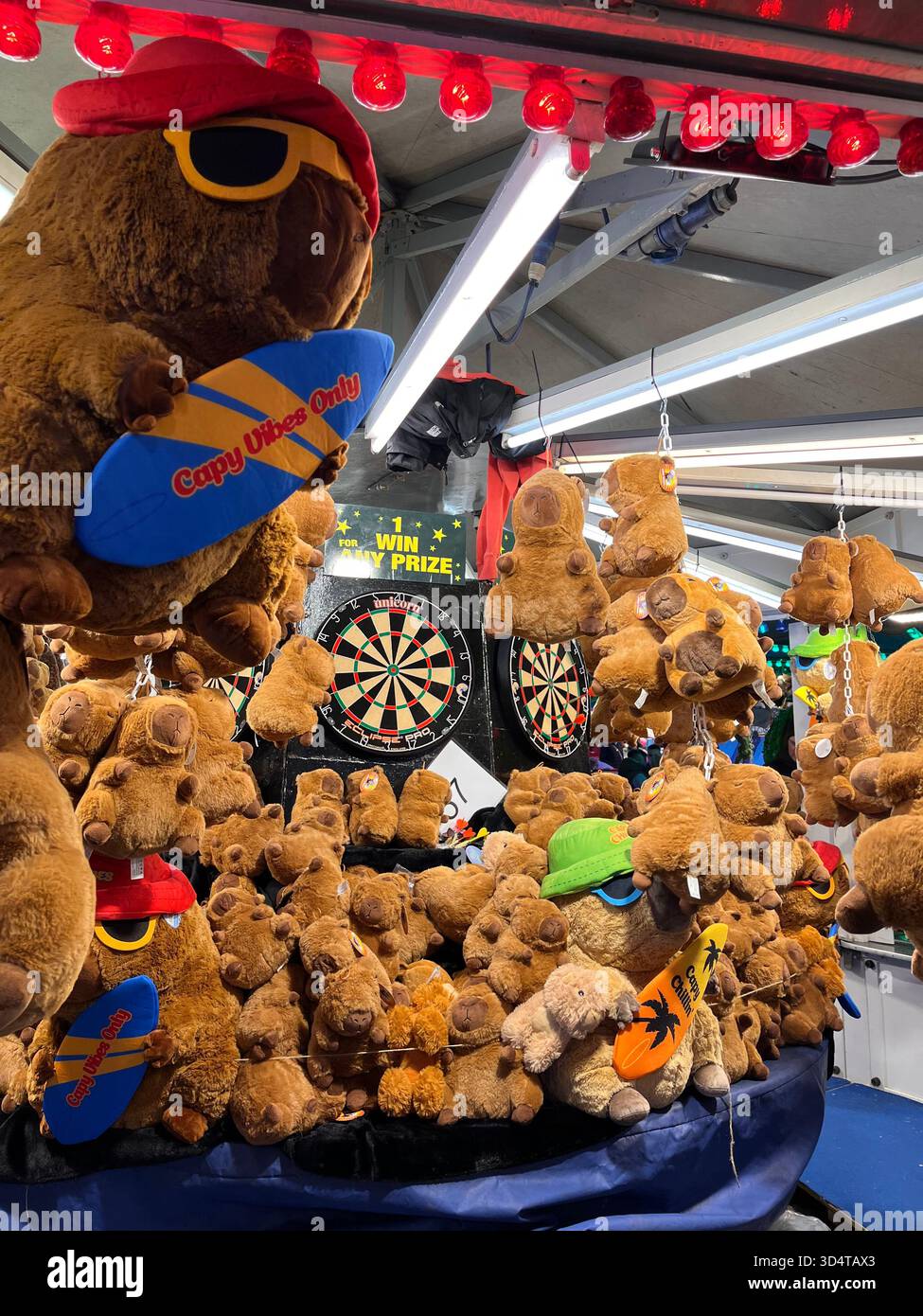 Una colorata platea di premi piena di peluche in una fiera notturna di Hull. Le luci accese illuminano orsacchiotti, giochi e decorazioni di carnevale. - Immagine stock catturata con smartphone