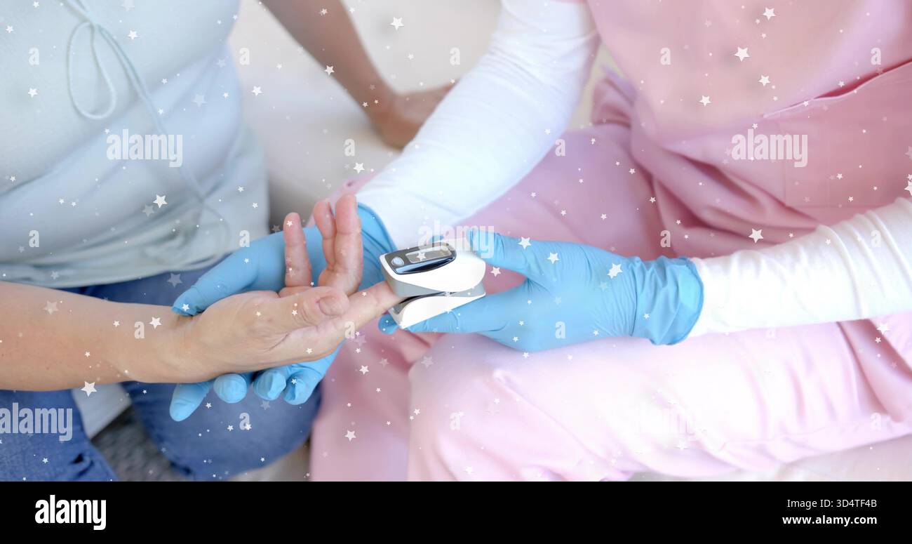 Guanti in nitrile blu per l'applicazione del pulsossimetro a casa, con scrub rosa e parte superiore azzurra Foto Stock