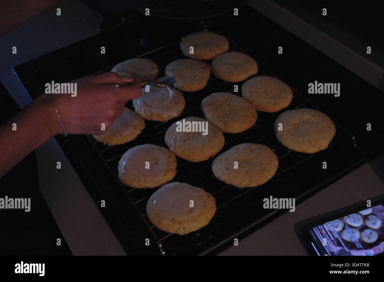 mettere una glassa sui biscotti appena sfornati Foto Stock