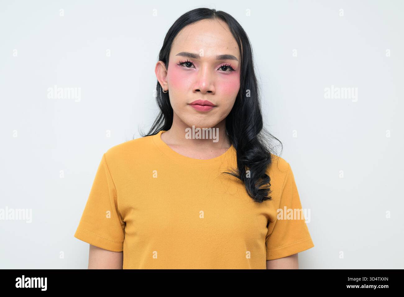 Ritratto in studio di un giovane individuo transgender thailandese con trucco e capelli lunghi. Concetto di espressione di genere, orgoglio LGBTQ e inclusività che mostra un Foto Stock