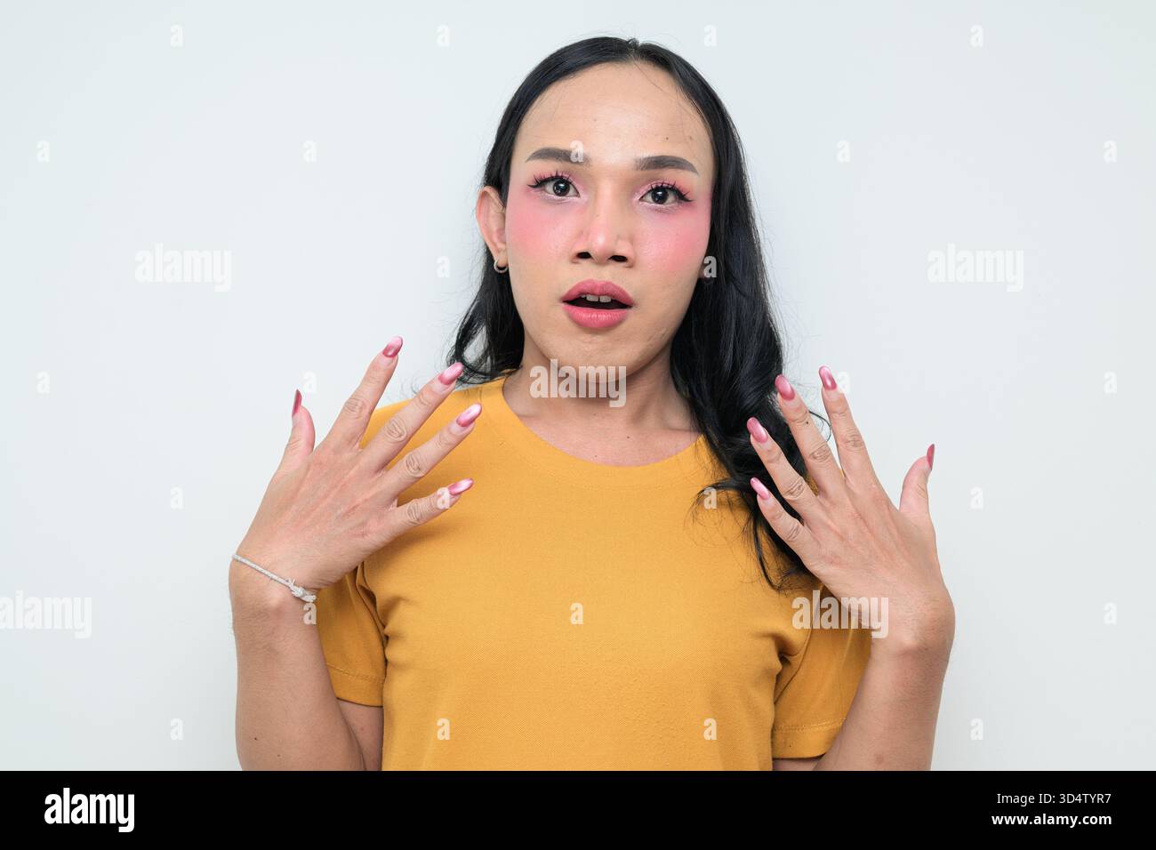 Ritratto in studio di un giovane individuo transgender thailandese con trucco e capelli lunghi. Concetto di espressione di genere, orgoglio LGBTQ e inclusività che mostra un Foto Stock