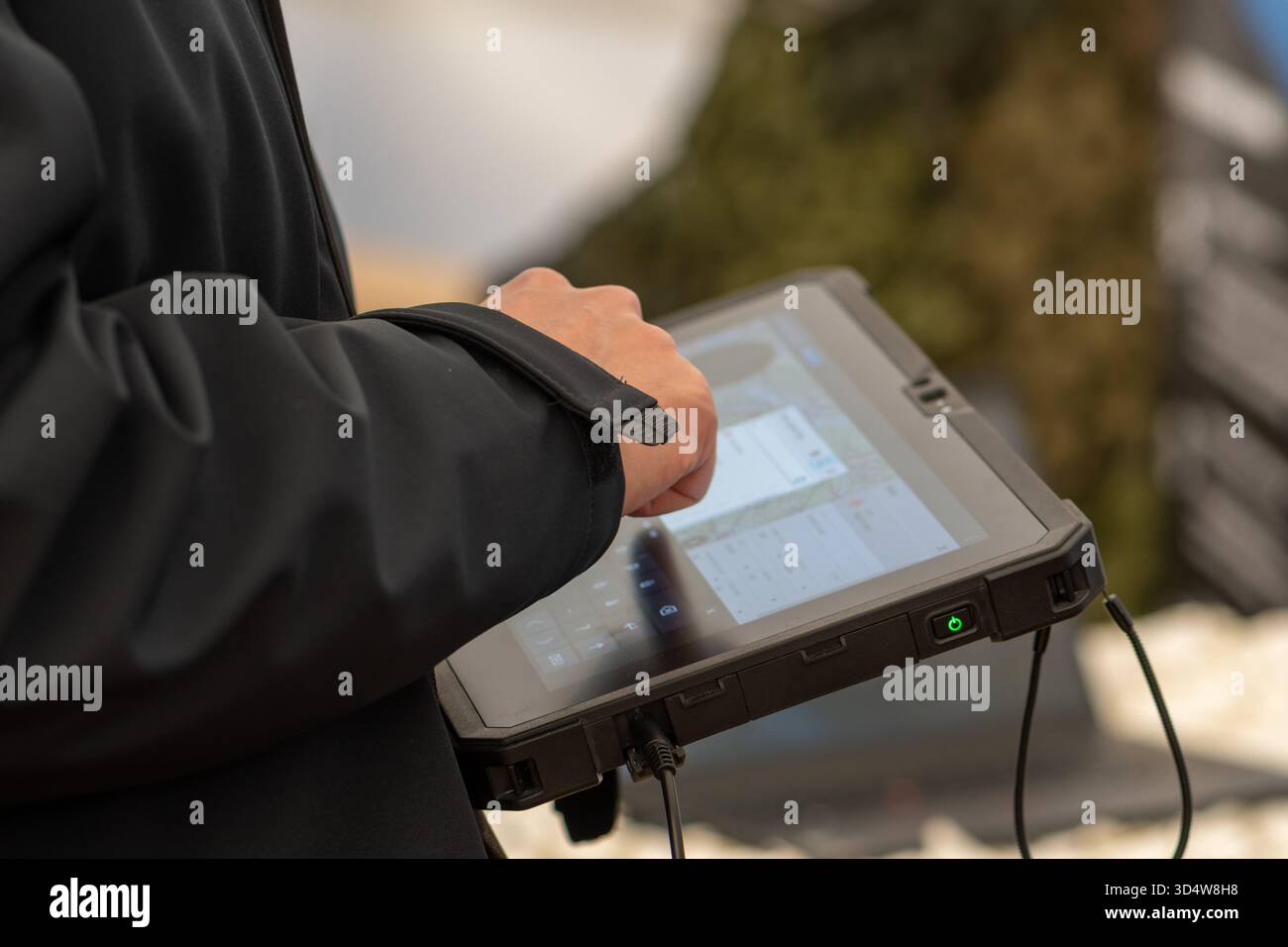 Un uomo con una giacca scura usa un tablet sicuro per controllare i sistemi militari Foto Stock