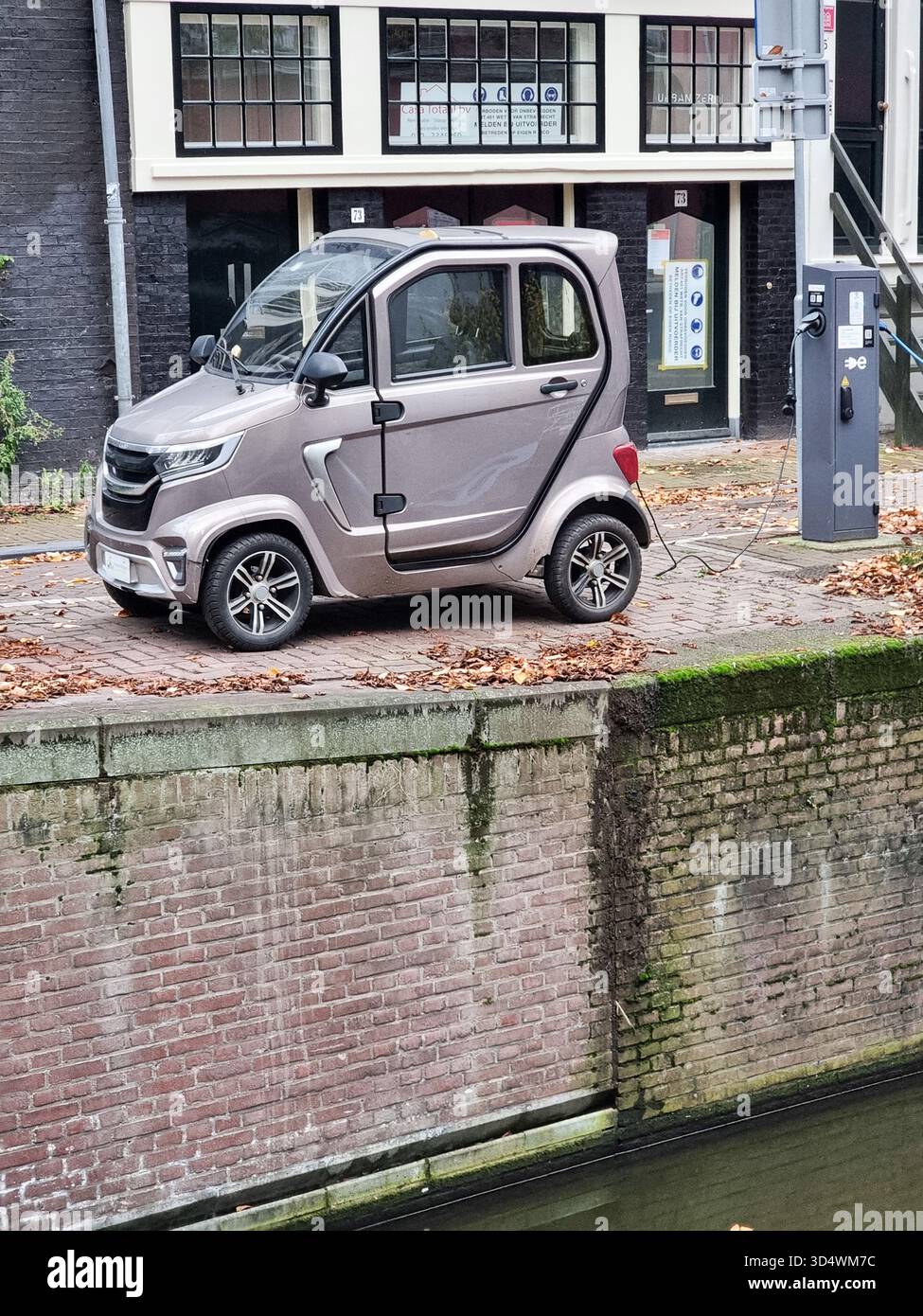Veicolo elettrico, microcar e-Car Motion Mirage, auto da città, ricarica collegata al polo di ricarica sul bordo del canale di Amsterdam, Paesi Bassi - Immagine stock catturata con smartphone