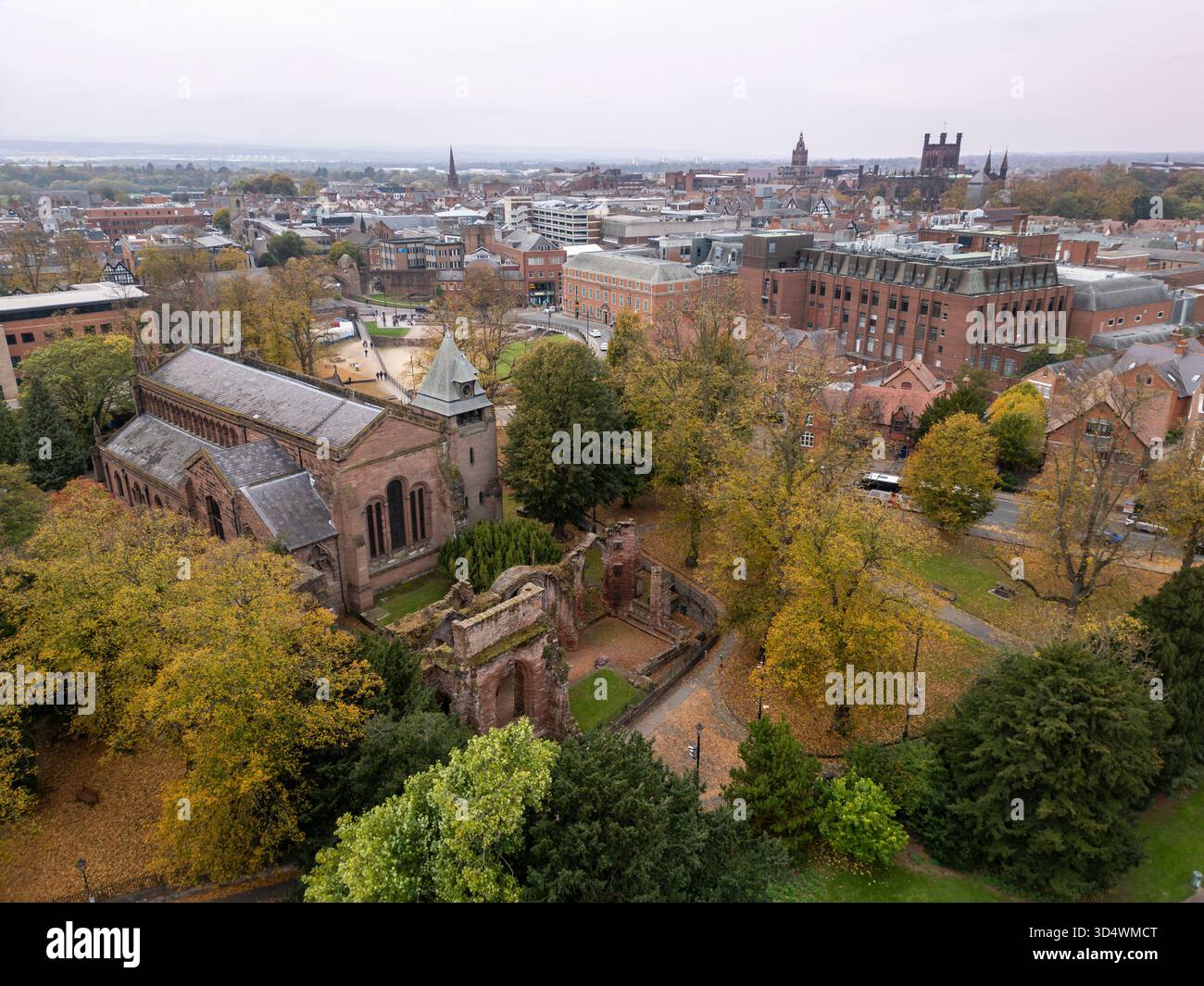 Chiesa di San Giovanni Battista a Chester, Cheshire, Inghilterra, circondata da alberi autunnali ed edifici cittadini Foto Stock