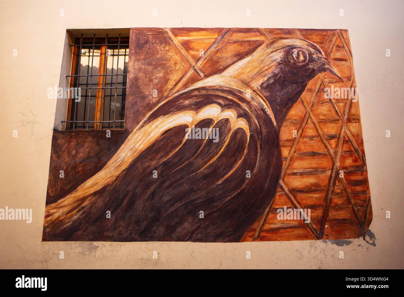 Murale artistico di un uccello stilizzato dipinto in calde tonalità terrose su una parete dell'edificio con sfondo geometrico arancione. Foto Stock