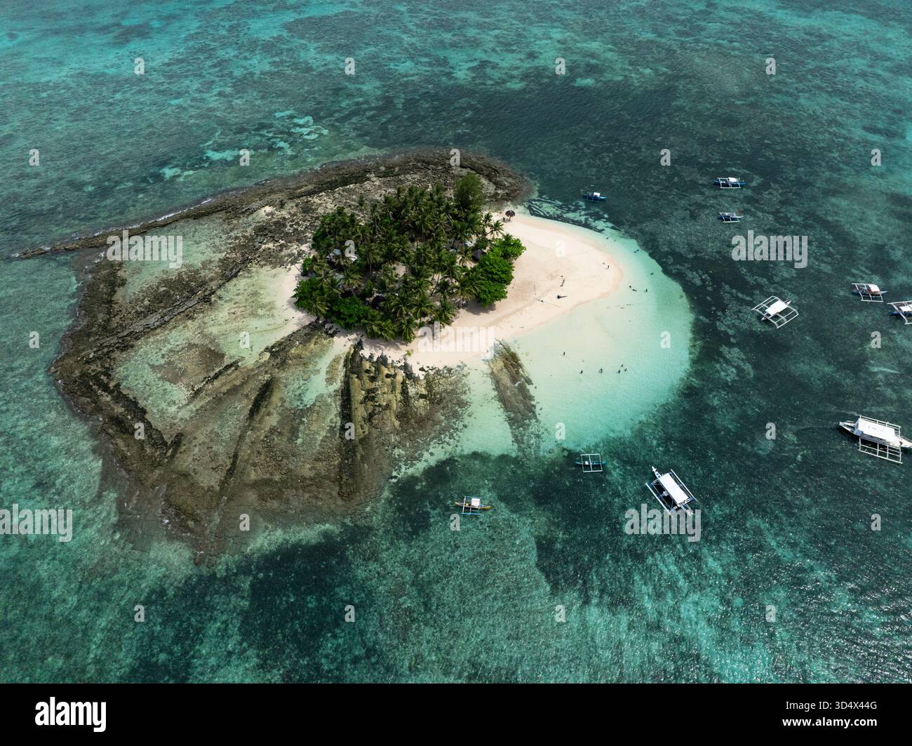 Vista droni dell'isola coperta da palme e spiaggia di sabbia bianca circondata dalla barriera corallina. Isola di Guyam. Siargao, Filippine. Foto Stock