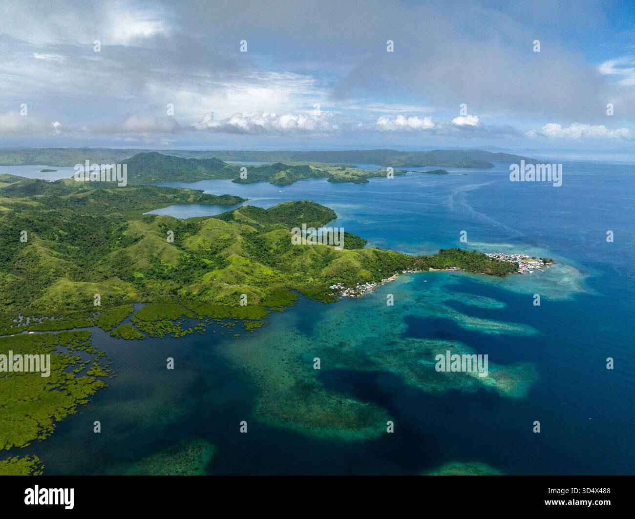 Villaggio costiero con case colorate vicino a montagne, mangrovie e acqua blu del mare. Siargao, Filippine. Foto Stock