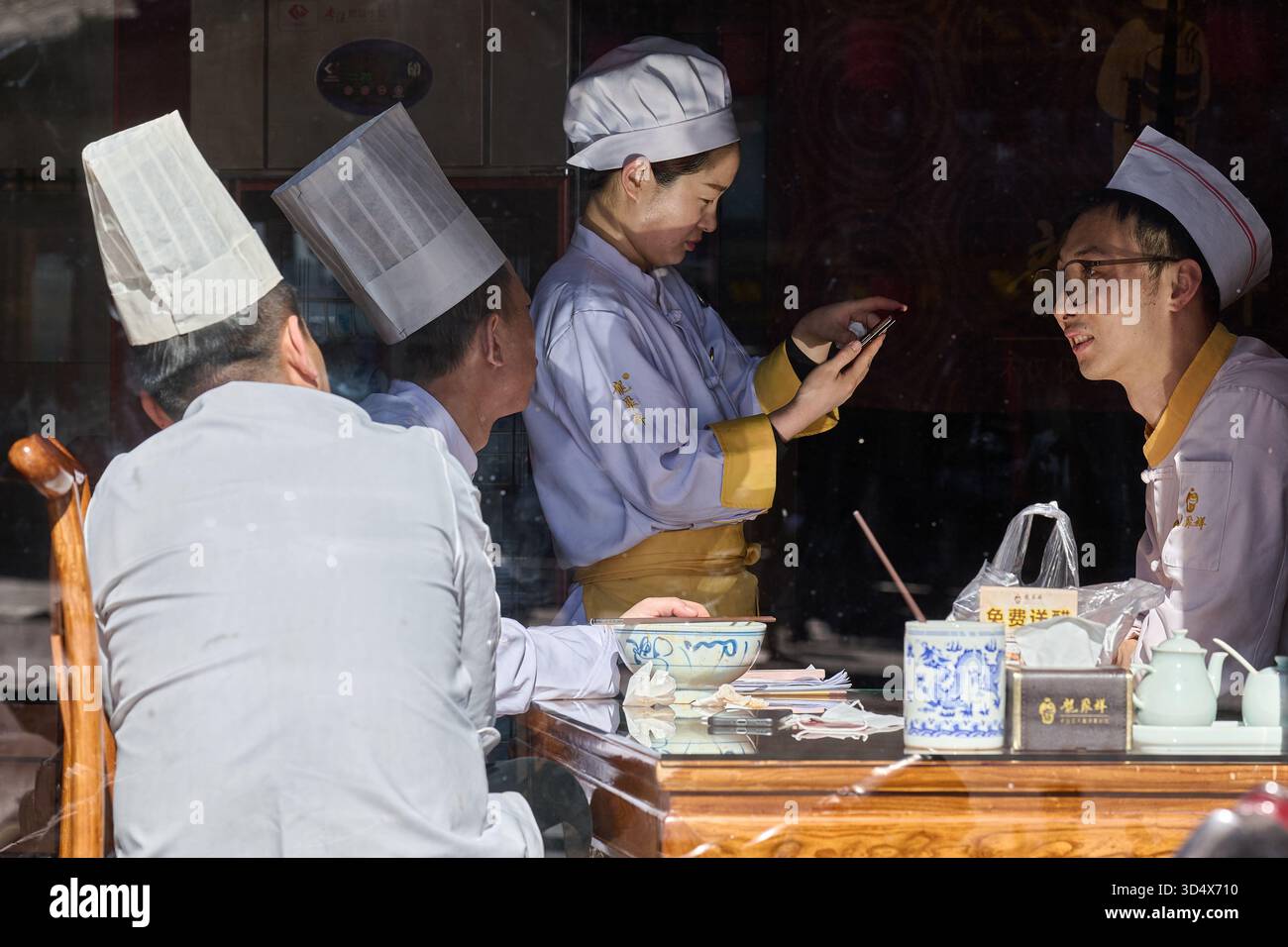 Interazione dello chef e dei clienti al banco della ristorazione, servizio professionale, ambientazione formale, giorno. Foto Stock