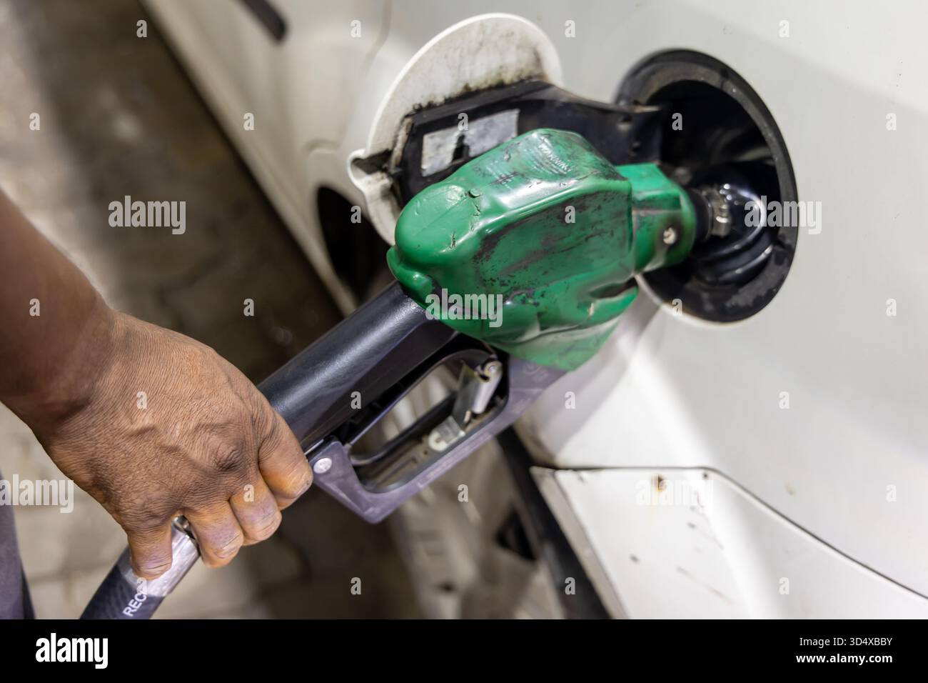 primo piano dell'auto di rifornimento manuale con ugello di benzina verde presso la stazione di servizio Foto Stock