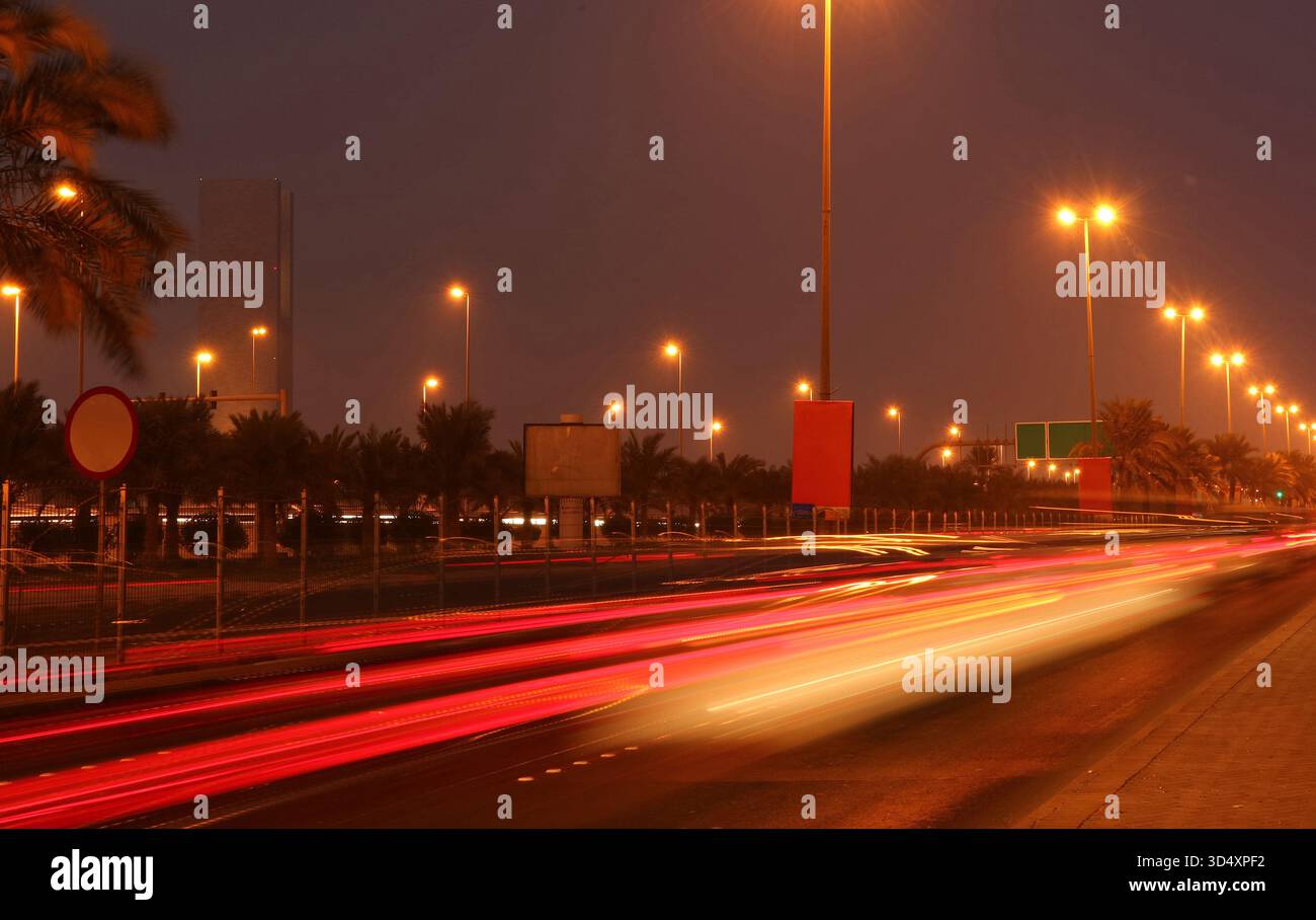 Strada urbana in città di notte con vivaci percorsi di luci per auto dai colori vivaci Foto Stock