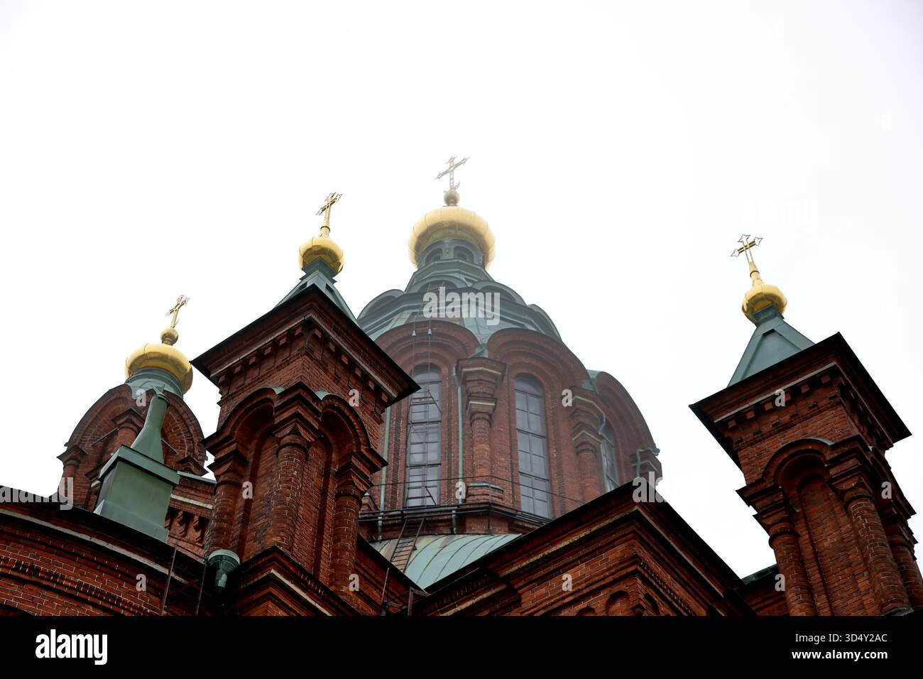 Torri architettoniche e cupola centrale della cattedrale di Uspenski con cipolle dorate a Helsinki, Finlandia, catturate da un'angolazione bassa in una giornata nebbiosa. Foto Stock