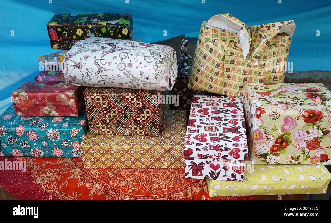 Pile di regali avvolti in carta a motivi batik sono stati presentati dagli ospiti all'ospite che stava celebrando un momento di felicità nella sua vita Foto Stock