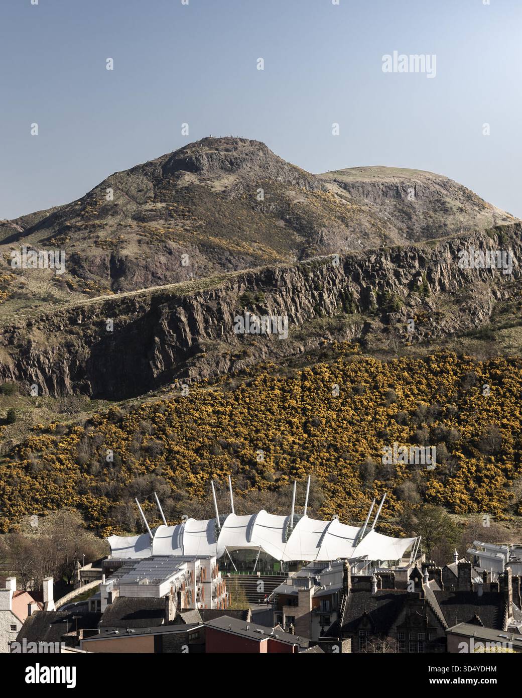 La vista dell'architettura moderna contrasta con l'aspra e naturale bellezza di una montagna sullo sfondo, bagnata dalla luce del sole, creando una sorprendente armonia visiva, Foto Stock