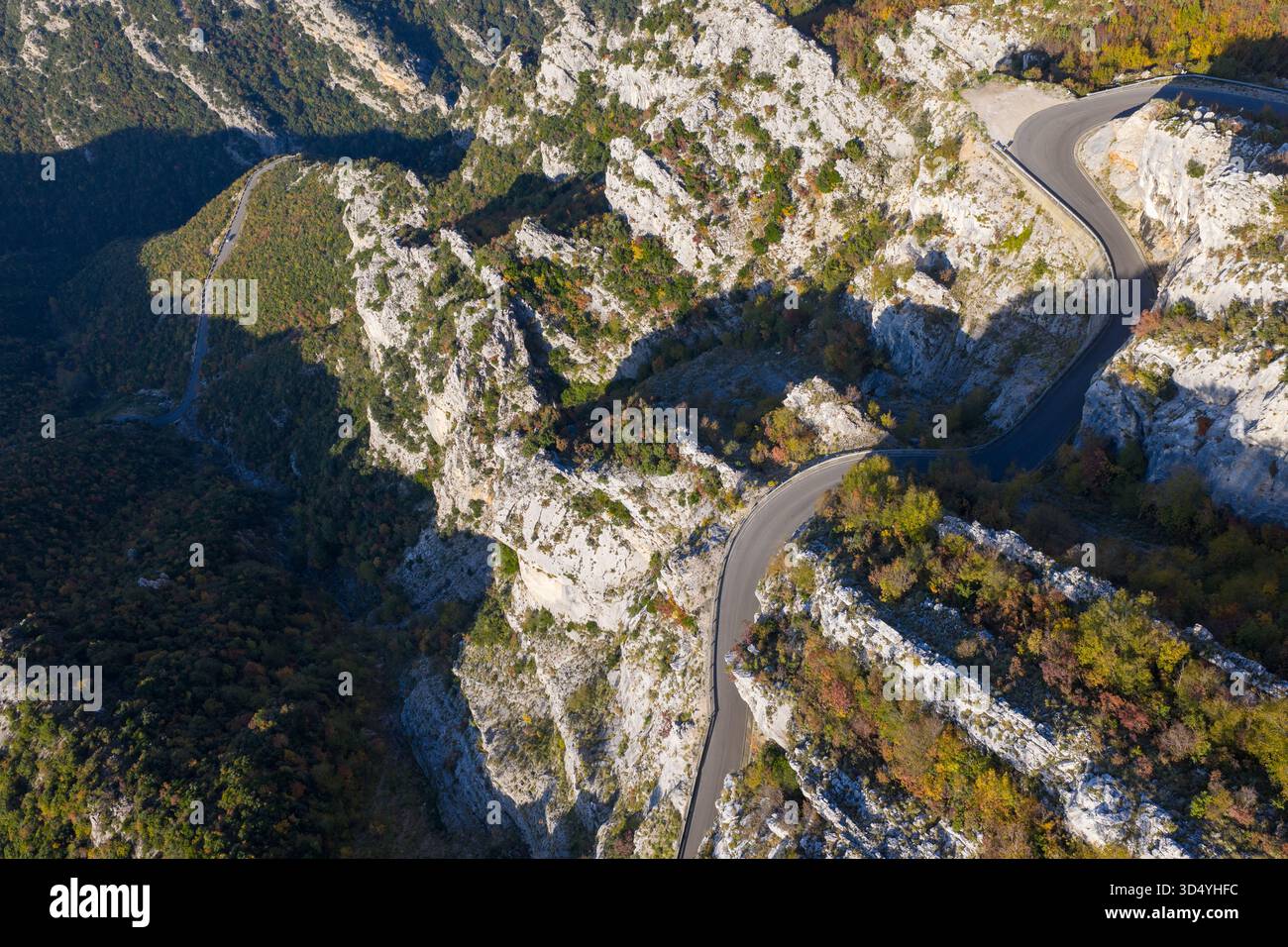 Immagine aerea della tortuosa strada di montagna di Krujë che attraversa ripide scogliere e pendii boscosi alla luce del sole dorato. Foto Stock