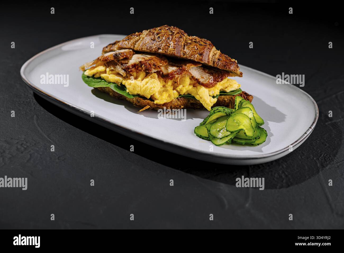 Cibo, deliziosi panini da colazione con croissant e uova strapazzate. Bacon. E avocado su un croissant appena sfornato. Perfetto per un salato e lui Foto Stock