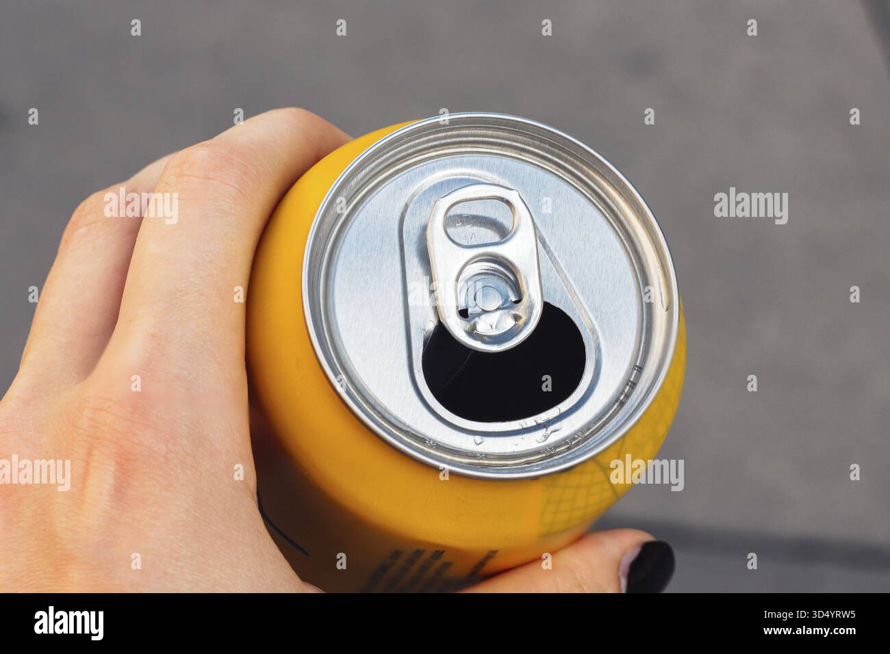Lattina gialla aperta con bevanda in mano, vista dall'alto Foto Stock