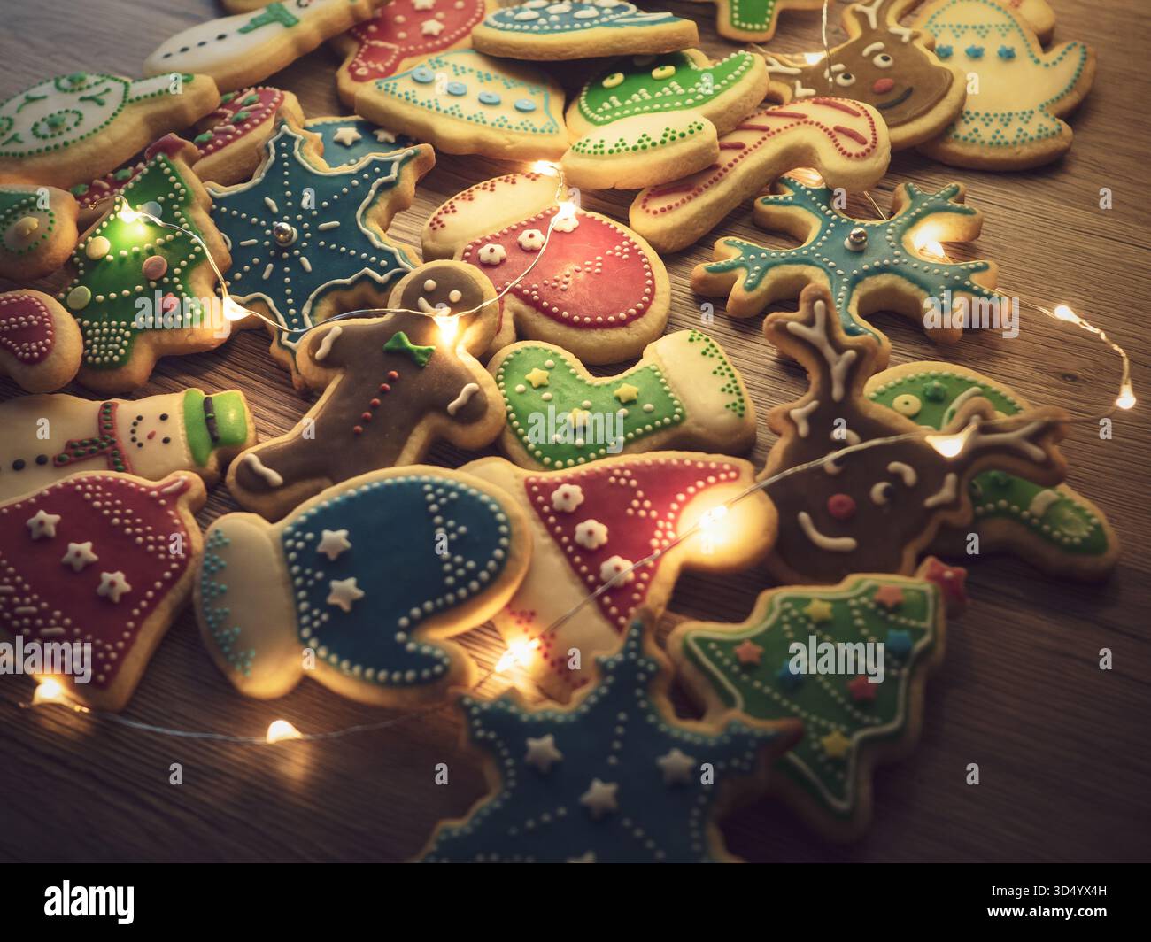 Biscotti di pan di zenzero natalizio con glassa colorata e luci, primo piano orizzontale per le feste Foto Stock