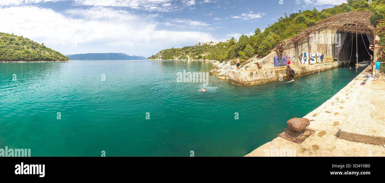Raba, Croazia - 7 luglio 2024: Rifugio della Marina jugoslava. Una bellissima baia con acqua verde acqua, con gente che nuota e tuffa sulla scogliera. C'è anche un ingresso al tunnel Foto Stock