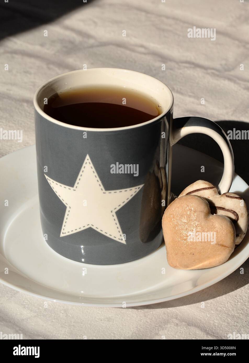 Tazza stellata con tè e biscotti a forma di cuore Foto Stock