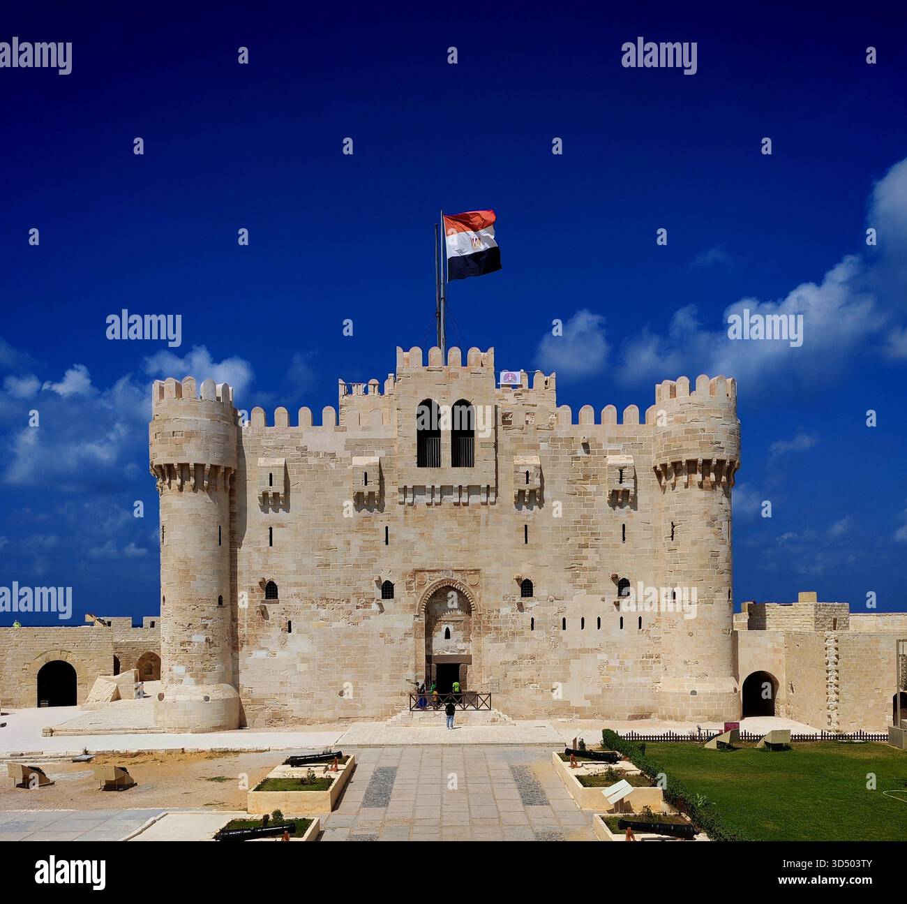 Cittadella di Qaitbay con bandiera egiziana sotto un cielo azzurro chiaro ad Alessandria, Egitto Foto Stock