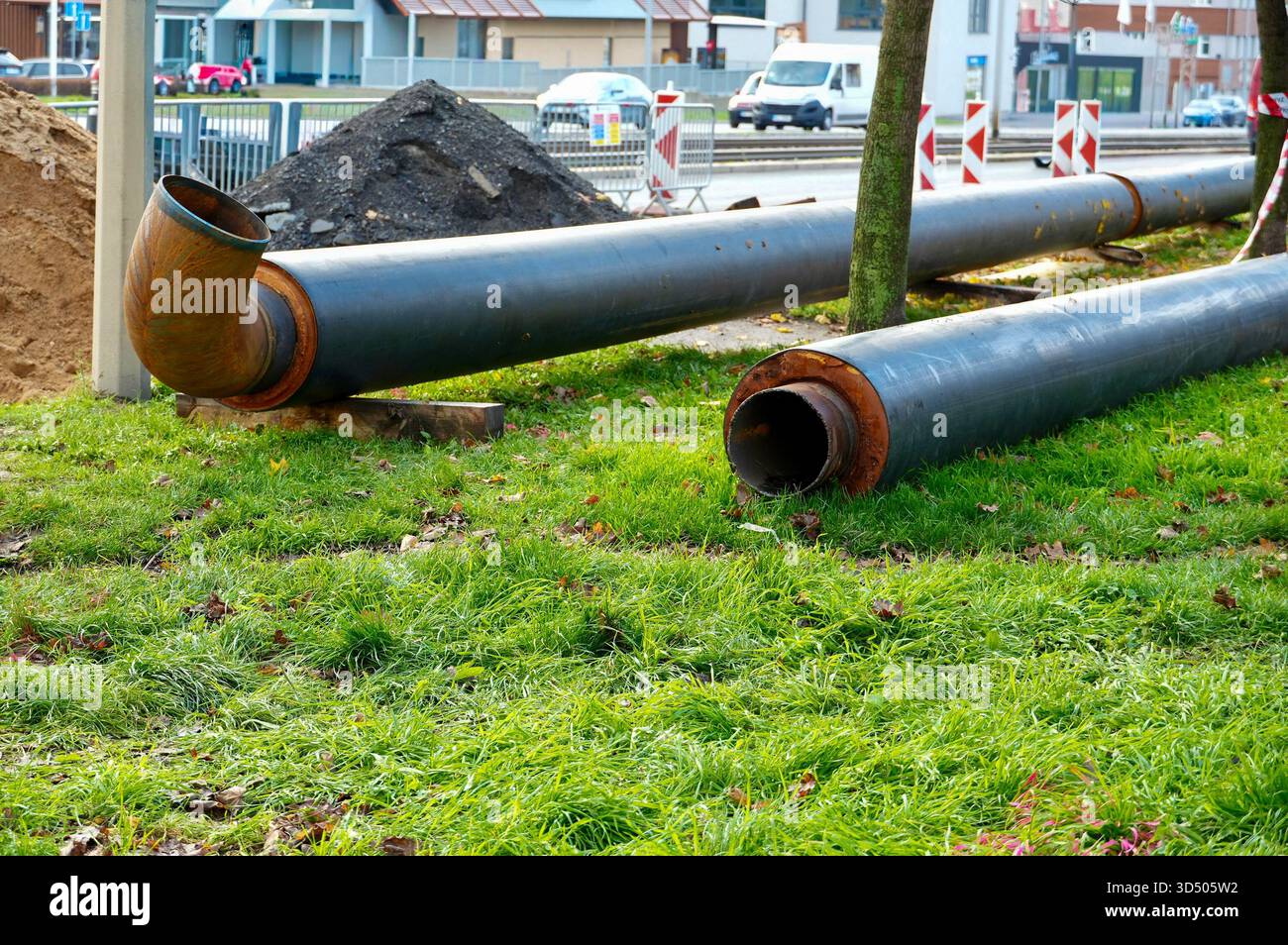 Tubi in un cantiere con erba verde, sullo sfondo di un'auto Foto Stock