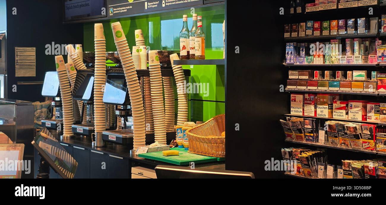 Berlino, Germania - 25 settembre 2025: Il bancone della caffetteria presenta tazze impilate e vari prodotti in esposizione per i clienti. - Immagine stock catturata con smartphone