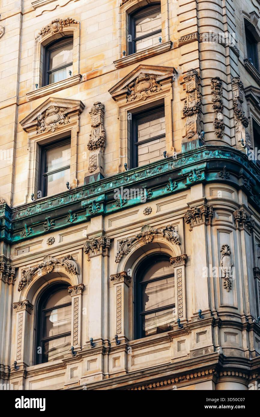 Montreal, Canada - 11 agosto 2025: Facciata dell'edificio storico con pietre ornate e dettagli in rame verde nel centro di Montreal, Quebec Foto Stock