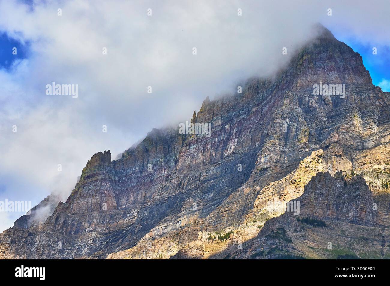 Il maestoso picco delle Montagne Rocciose con spettacolare copertura nuvolosa e pareti rocciose illuminate dal sole Foto Stock