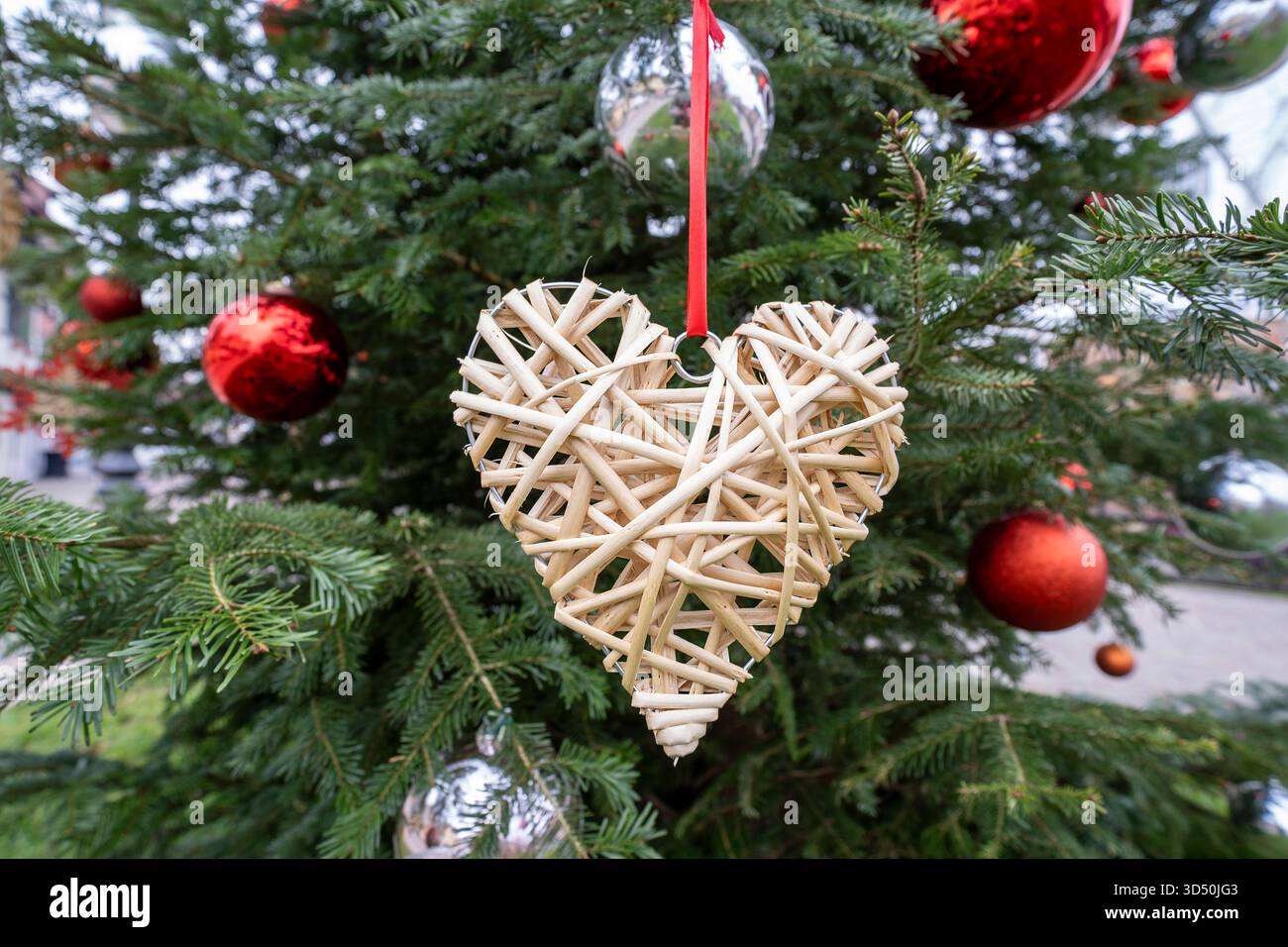Ornamento a forma di cuore che adorna un albero di Natale con luci Foto Stock