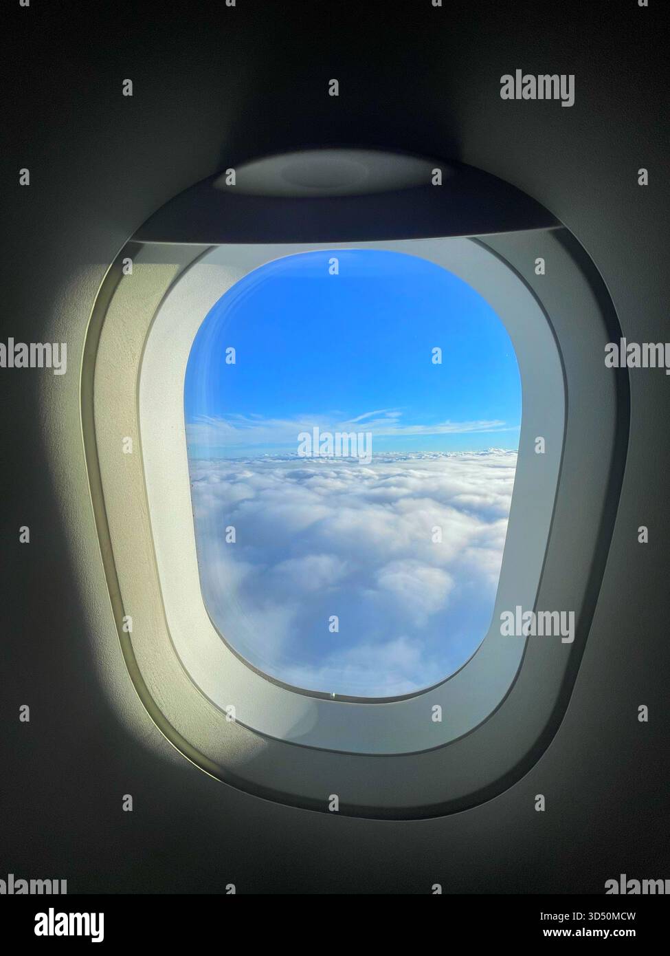 Vista dalla finestra dell'aeroplano che mostra il cielo azzurro e gli strati di nuvole, catturando la serenità del viaggio in alta quota Foto Stock
