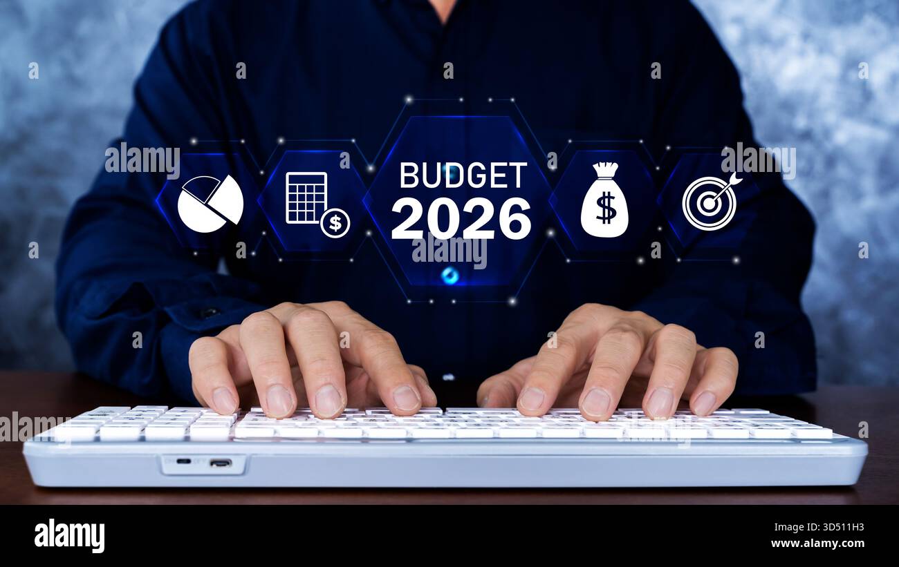 Uomo d'affari che digita sulla tastiera con interfaccia digitale budget 2026 che mostra icone finanziarie, analisi, risparmi e obiettivi target. Concetto di p. Finanziaria Foto Stock