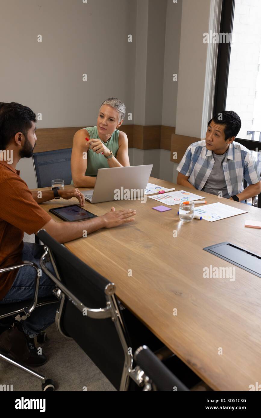 Incontro con colleghi diversi che condividono idee al tavolo da conferenza nella sala riunioni, con tablet e grafici Foto Stock