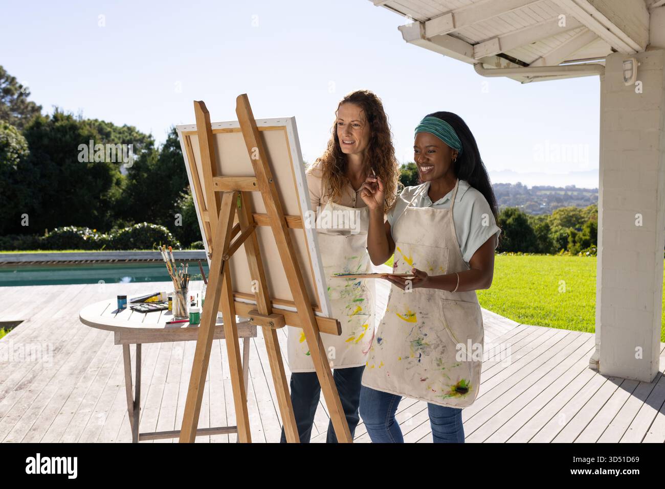Dipingendo diverse amiche in piedi su una tavola di legno, con cavalletto in legno e forniture di pittura Foto Stock