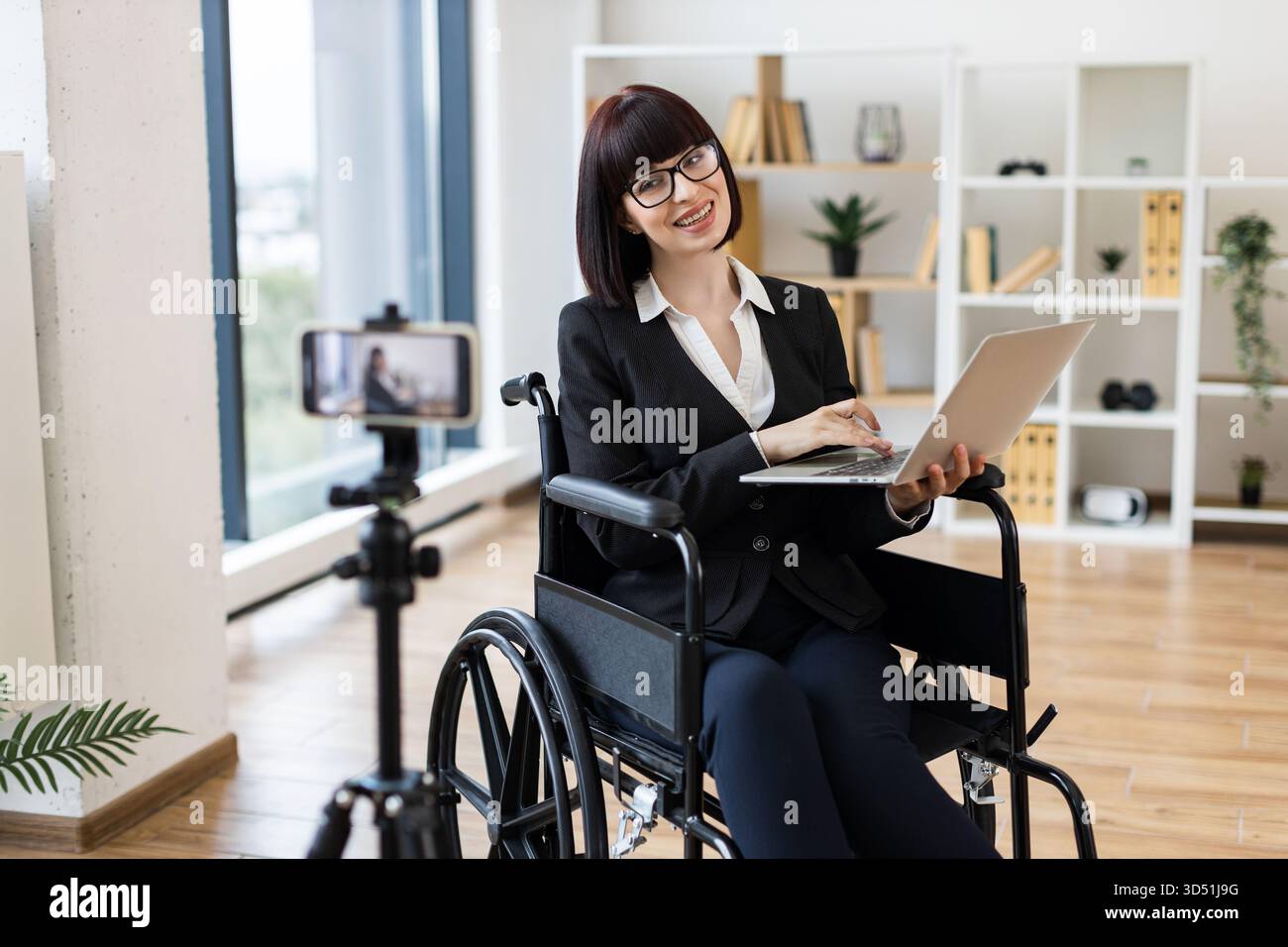 Donna caucasica in una sedia a rotelle che scrive su affari con la configurazione della fotocamera Foto Stock