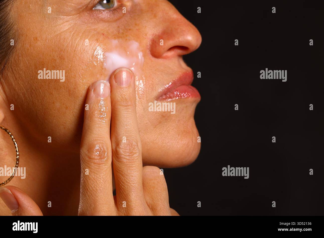Donna che applica crema idratante al suo viso — cura della pelle e trattamento di bellezza per una pelle sana e luminosa Foto Stock