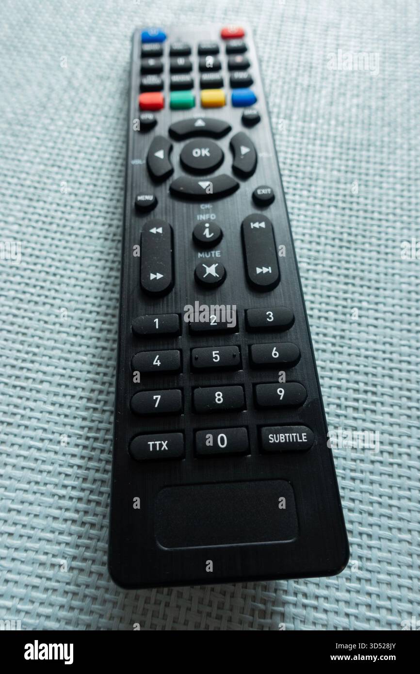 Telecomando TV nero su una superficie ruvida con pulsanti per il funzionamento dei dispositivi di intrattenimento Foto Stock