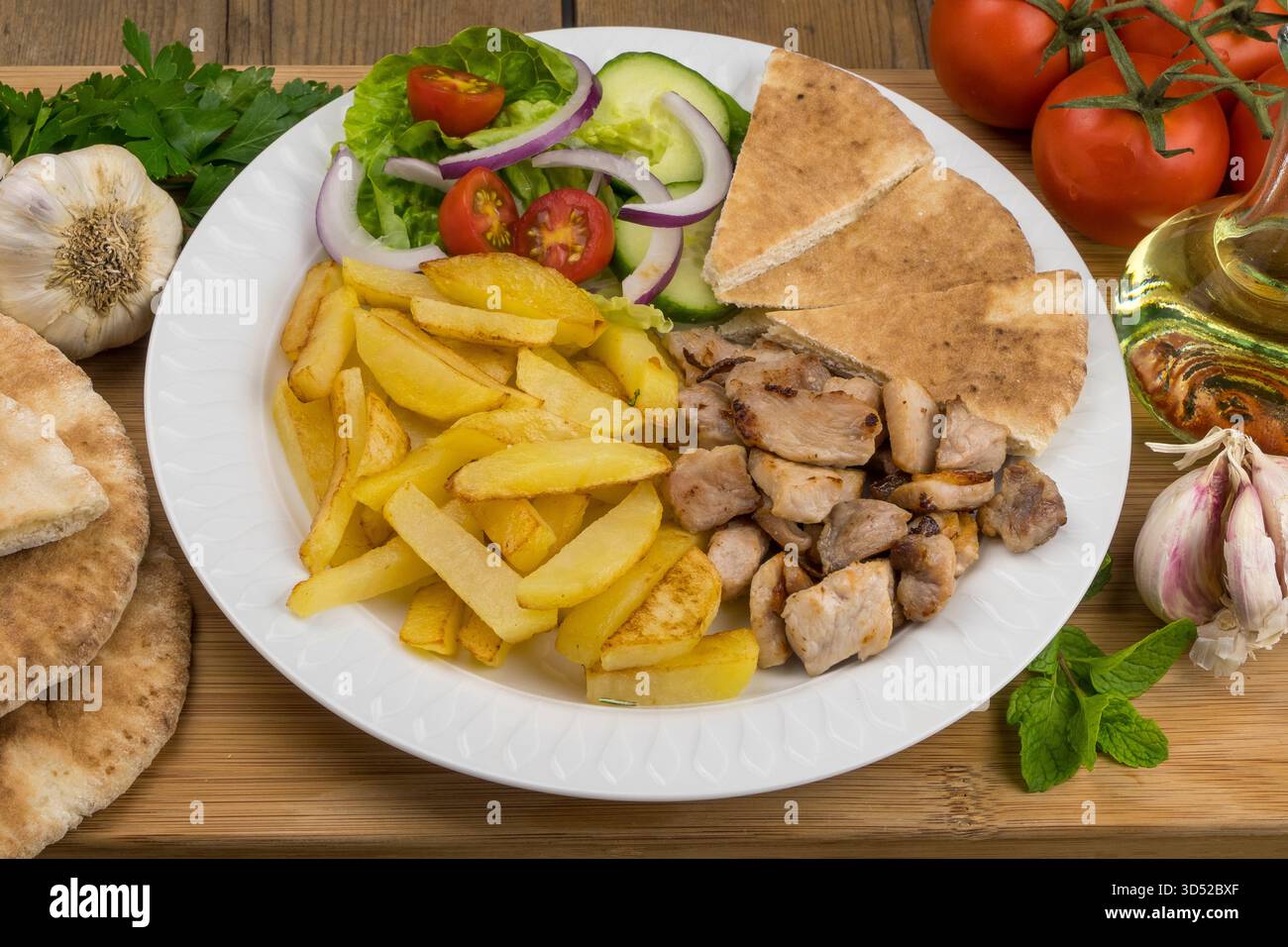 Carne, patatine fritte, pane pita e insalata su un tavolo Foto Stock