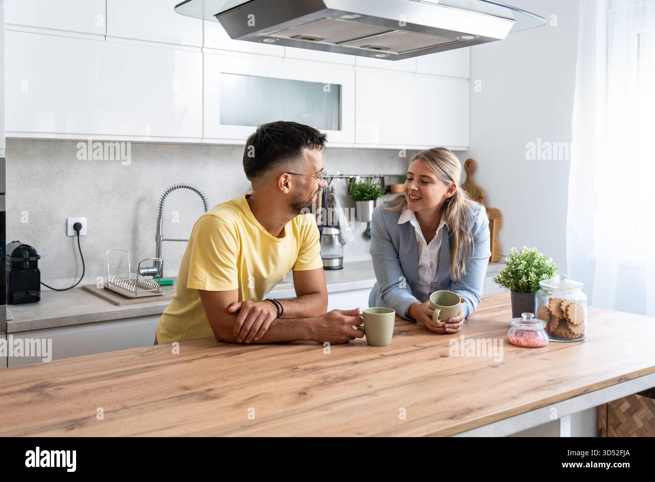 Una donna d'affari in un blazer parla con il suo partner vestito in modo informale per un caffè prima di lavorare allineando i piani per la chiamata del cliente, sincronizzando i programmi e gli obiettivi, Foto Stock