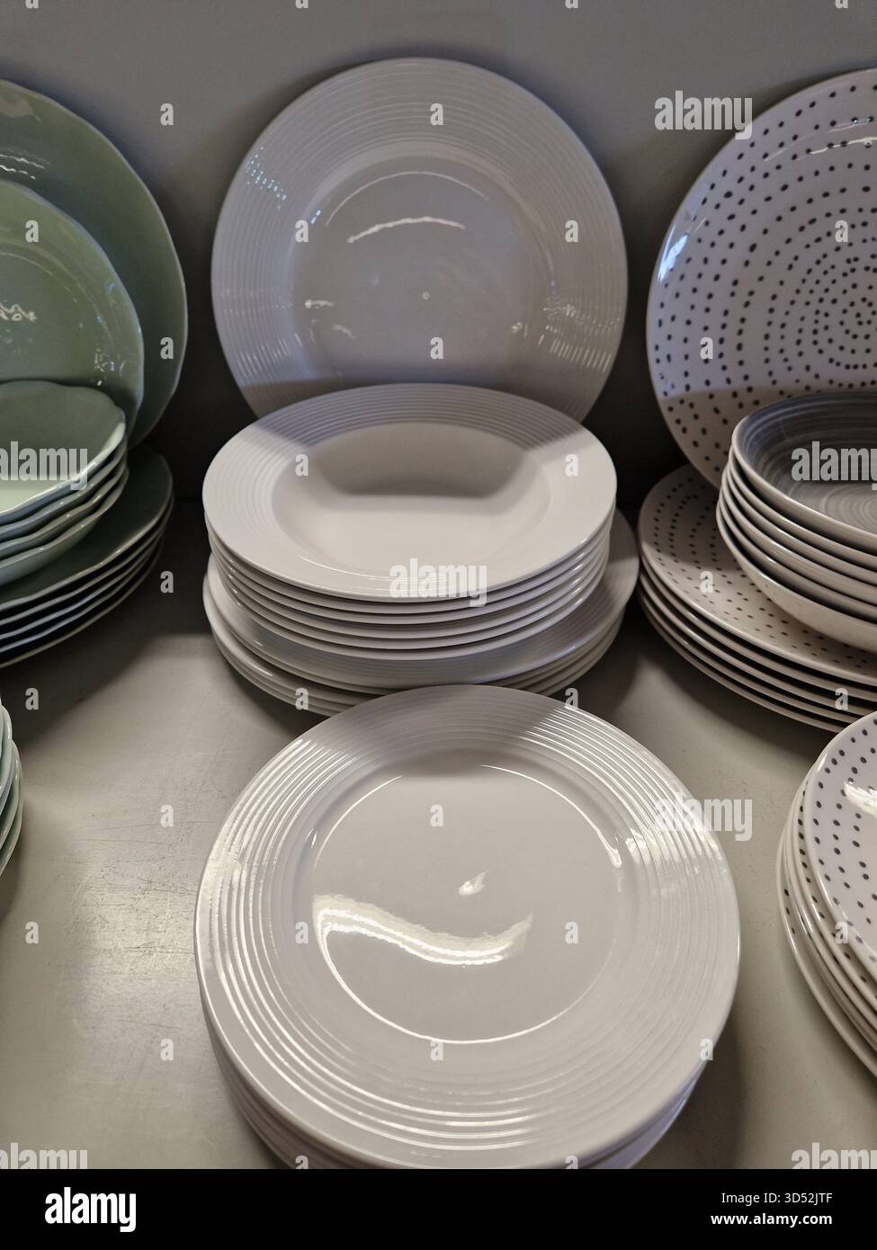 Piastre in ceramica impilate in colori neutri visualizzate su un ripiano. Design semplice ed elegante con linee pulite e motivi minimali. Foto Stock
