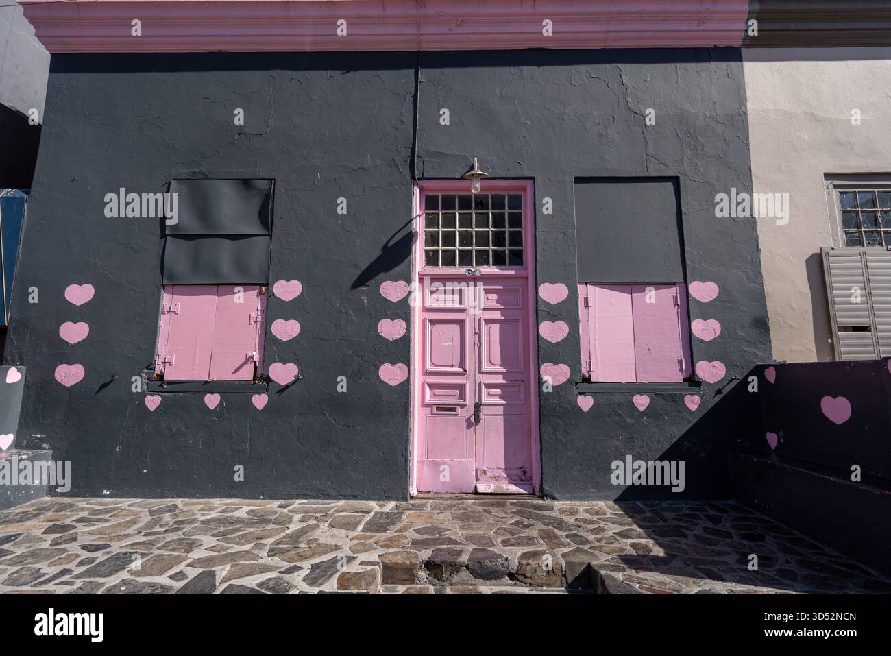 Edificio nero con porte e finestre rosa luminose con decorazioni pin keart Bo-Kaap, città del Capo, Sud Africa Foto Stock