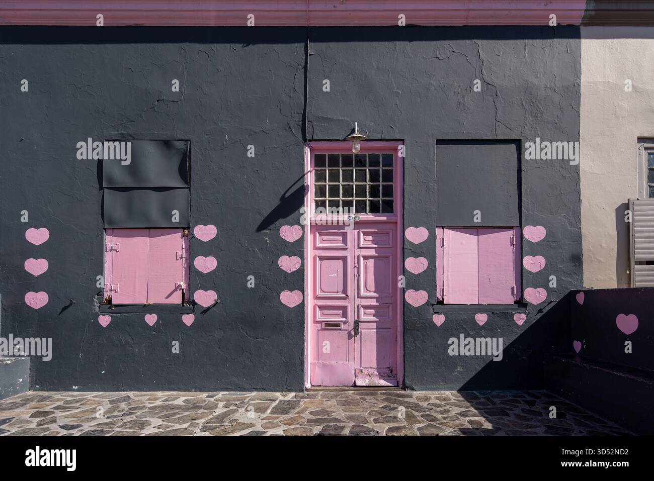 Edificio nero con porte e finestre rosa luminose con decorazioni pin keart Bo-Kaap, città del Capo, Sud Africa Foto Stock