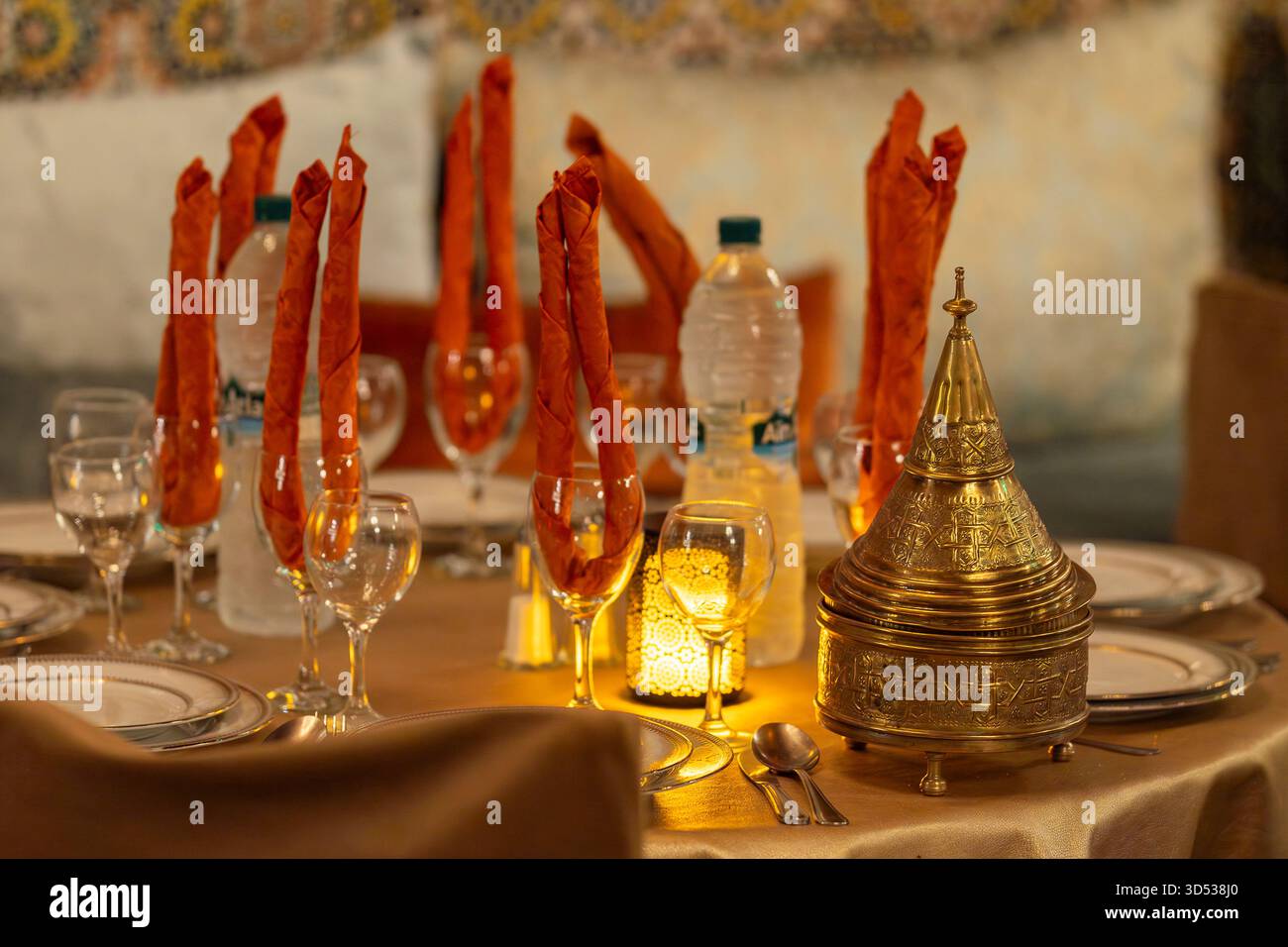 Elegante ambiente da tavola in un tradizionale ristorante marocchino con luce calda. Tavolo da pranzo a tema arabo, contenitore in stile marocchino con coperchio. Foto Stock
