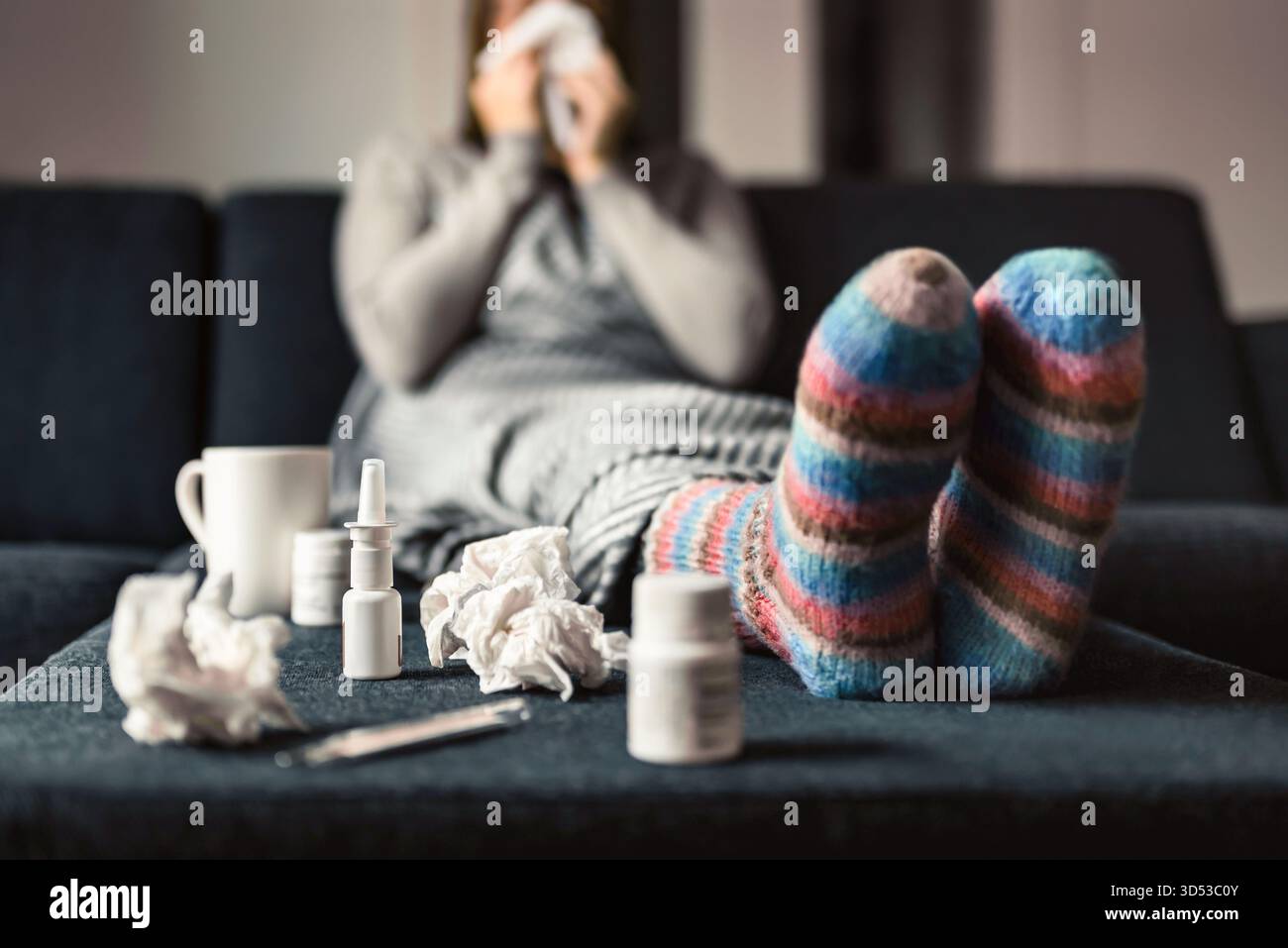 Influenza o influenza. Malato e malato durante il freddo inverno. Donna con i calzini. Spray per naso per farmaci allergici o antifebbre. Persona che starnutisce su un asciugamano di carta. Foto Stock