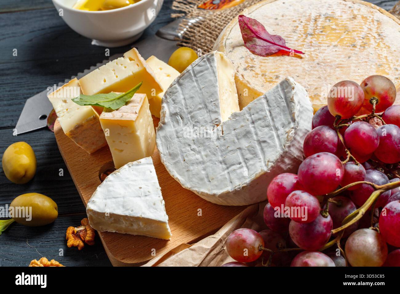 Delizioso vassoio di formaggi con uva e olive per uno spuntino perfetto Foto Stock