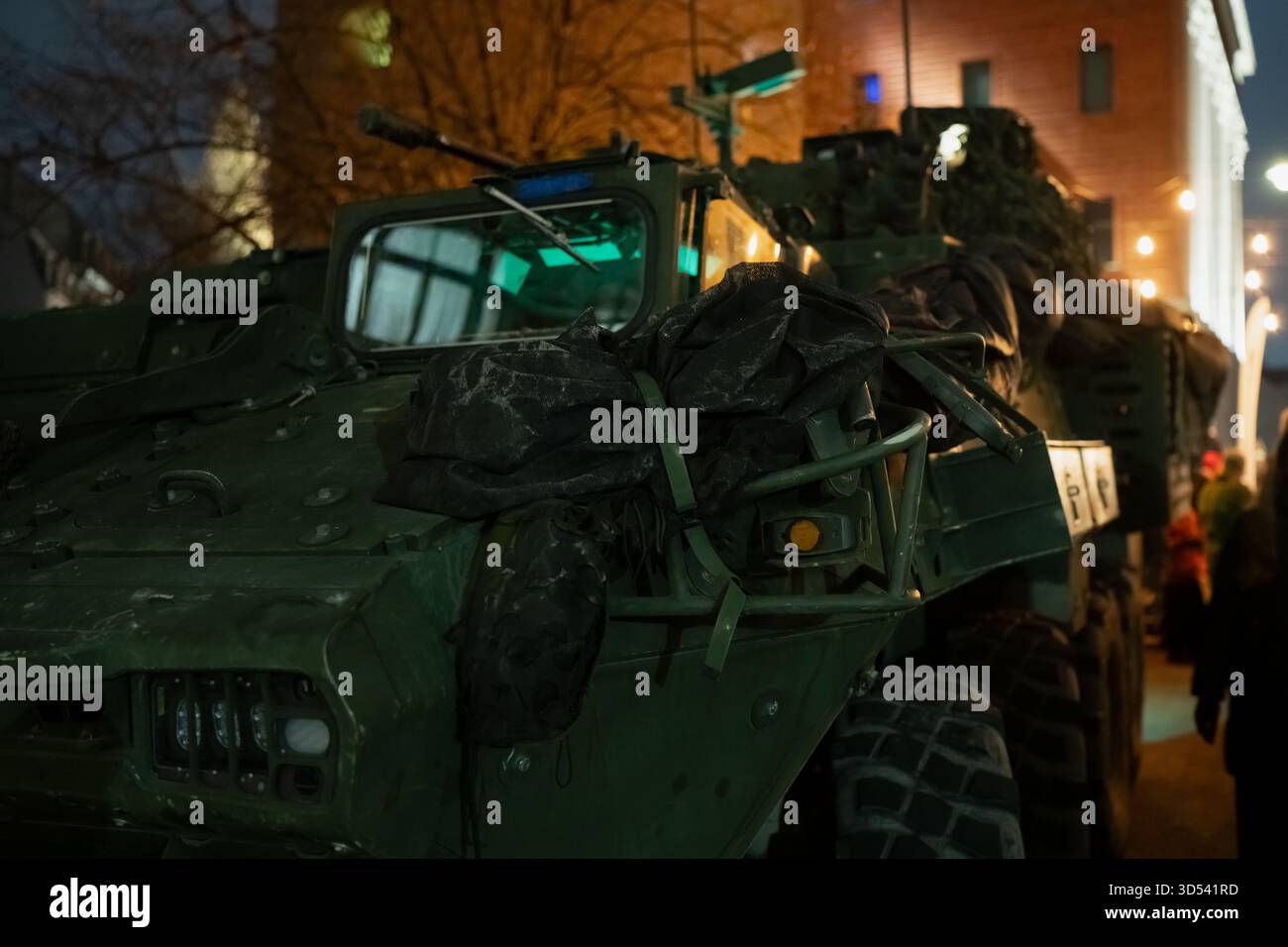 Veicolo militare corazzato esposto a riga di notte con equipaggiamento tattico visibile, coperture protettive e attrezzature montate, che mettono in risalto le robuste strutture Foto Stock