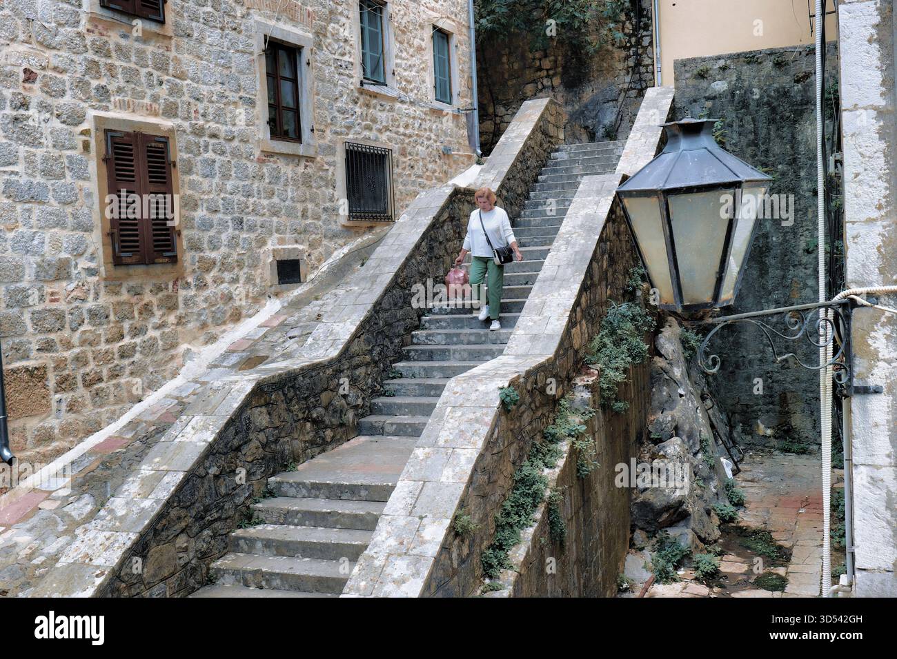 Donna che cammina giù per le scale nella città vecchia di Cattaro, in Montenegro Foto Stock