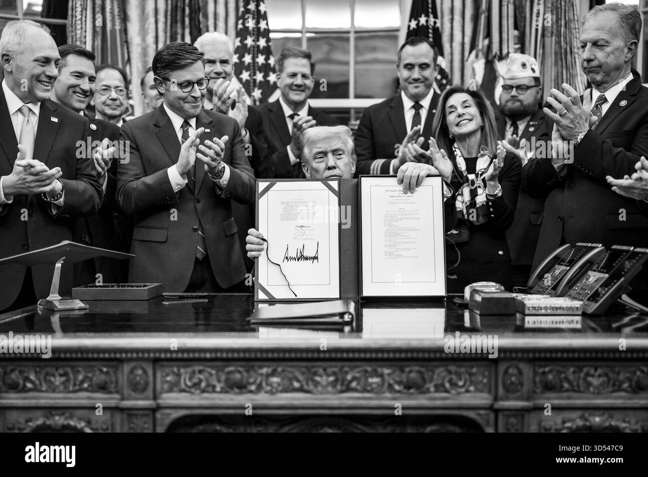 Il presidente Donald Trump mostra ai membri dei media il disegno di legge firmato dal Congresso che riapre il governo, mercoledì 12 novembre 2025, nell'Ufficio ovale. (Foto ufficiale della Casa Bianca di Daniel Torok) Foto Stock